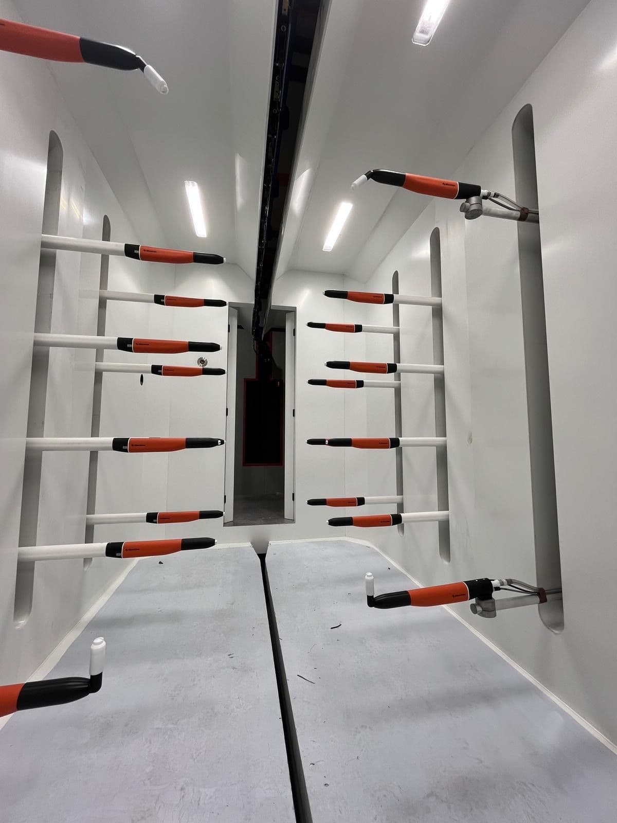 Interior of a powder coating booth with automatic guns mounted on both side walls