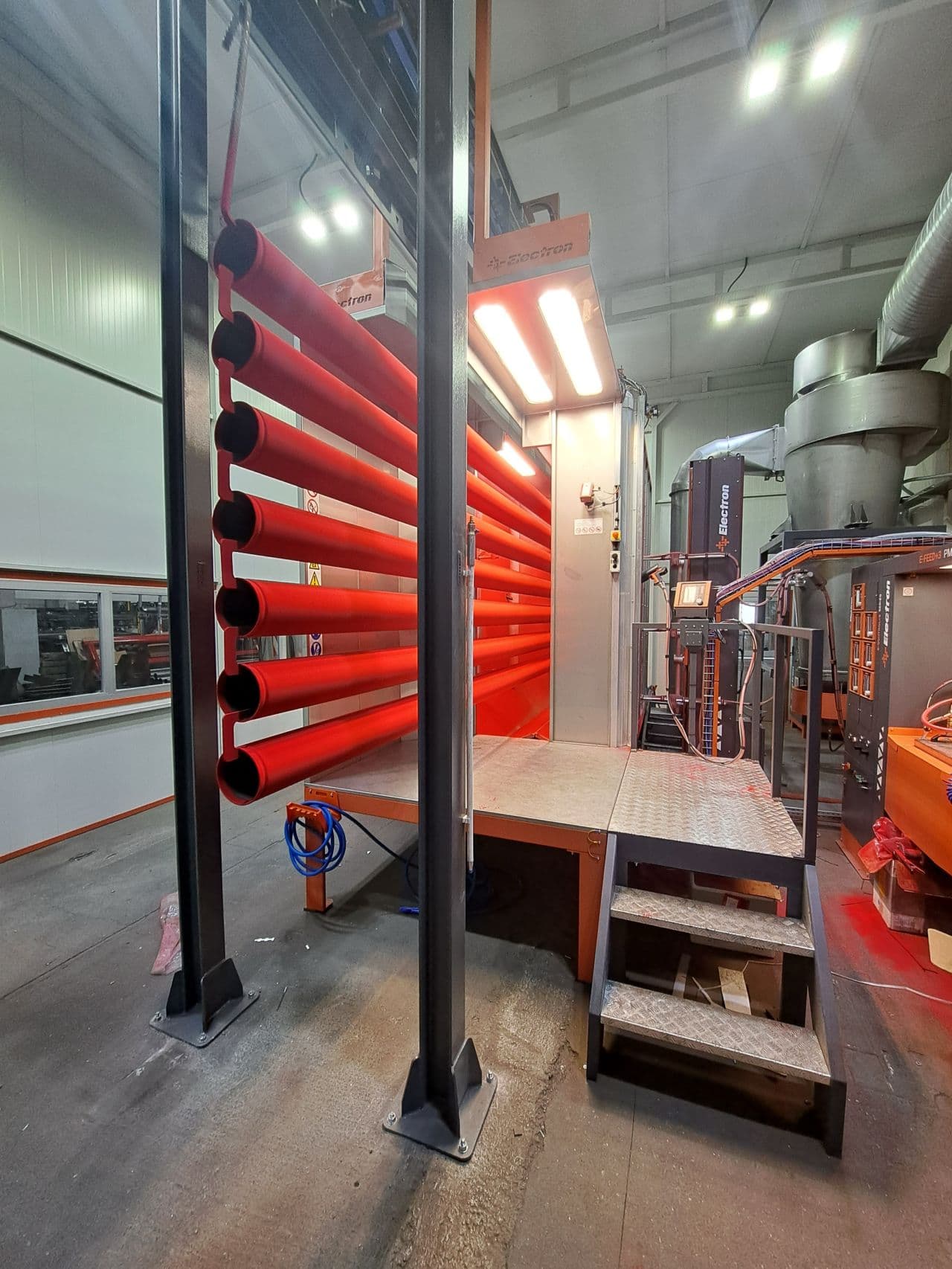 Powder coating booth interior with an overhead automatic gun rack and raised access platform